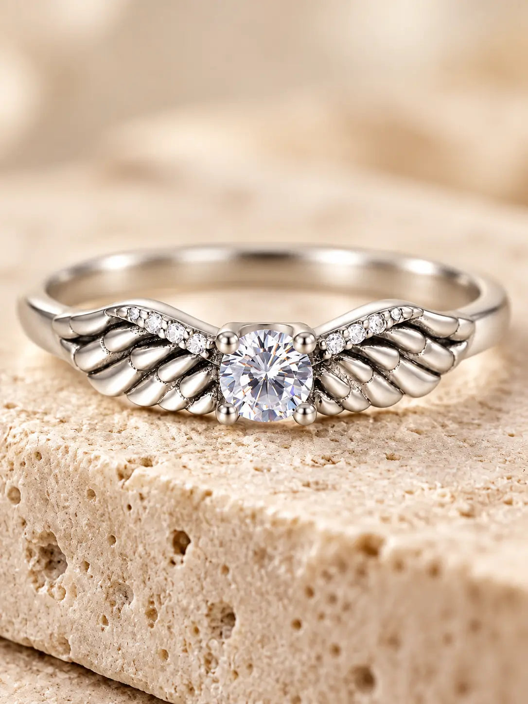Close-up of Yeneast angel wing ring showing sculpted feather details, pavé accents and a brilliant round center stone.