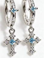 Close-up detail of YENEAST gemstone cross hoop earrings showing blue sapphire stones, pavé accents, polished silver finish and fine craftsmanship.