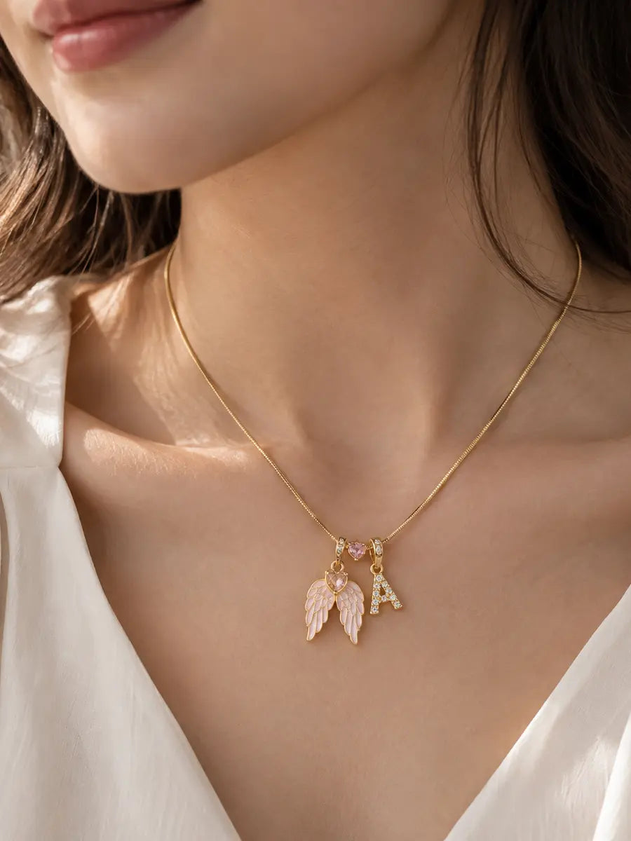 Woman wearing YENEAST personalized angel wings initial necklace with pink wings and crystal letter charm