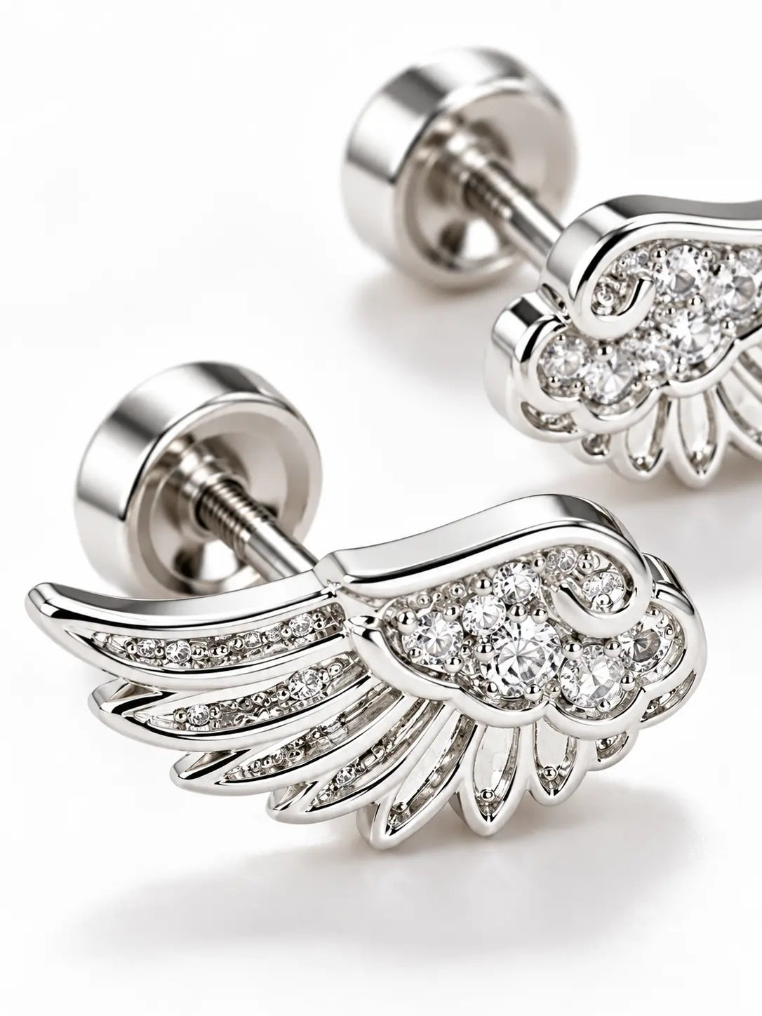 Close-up detail of YENEAST silver angel wing earrings showing crystal pavé setting, feather texture, polished metal and fine craftsmanship.